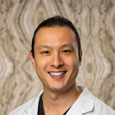 Dentist Alan Liu Smiling In Lab Coat